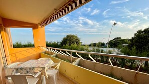A balcony with a table and chairs, overlooking a body of water and greenery.