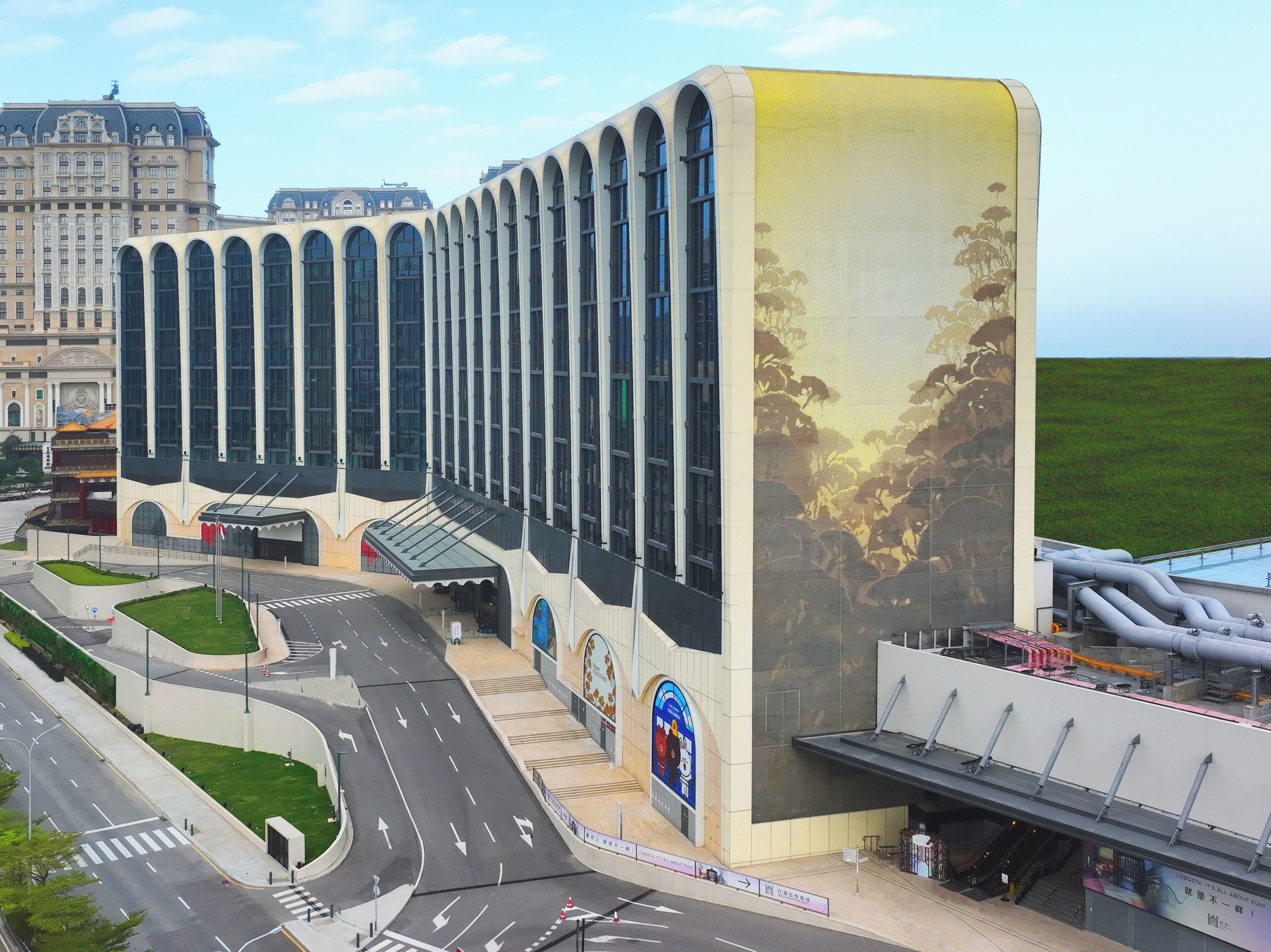 Un bâtiment moderne doté d’une grande entrée en arc de cercle et d’une fresque murale sur le côté.