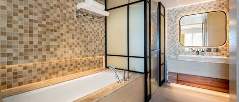 Un baño moderno con una bañera grande, cabina de ducha de vidrio y tocador con espejo.