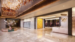 Un hall d’entrée spacieux, doté d’un comptoir de réception, d’une composition florale décorative et d’un lustre moderne.