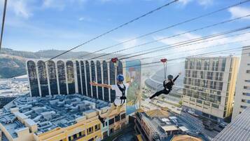 A high-altitude ziplining activity with participants suspended on cables above a cityscape.