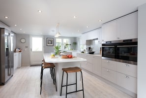 A modern kitchen with a central island, stainless steel appliances, and ample natural light.
