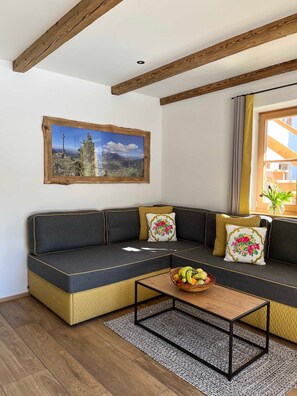A modern living room with a sectional sofa, a wooden coffee table, and a framed landscape painting. - Sunnseitn, Germany (Bayrischzell)