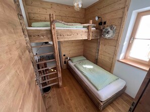 Ein Zimmer mit einem hölzernen Etagenbett, einer kleinen Schreibtisch und einem Fenster.