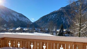 Un balcon donnant sur un paysage montagneux enneigé et sur des maisons.