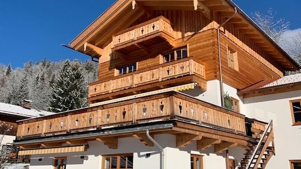 Un chalet en bois à plusieurs étages, doté de balcons et d’un escalier.