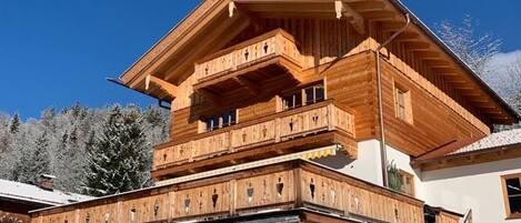 Una cabaña de madera de varios pisos con balcones y una escalera.