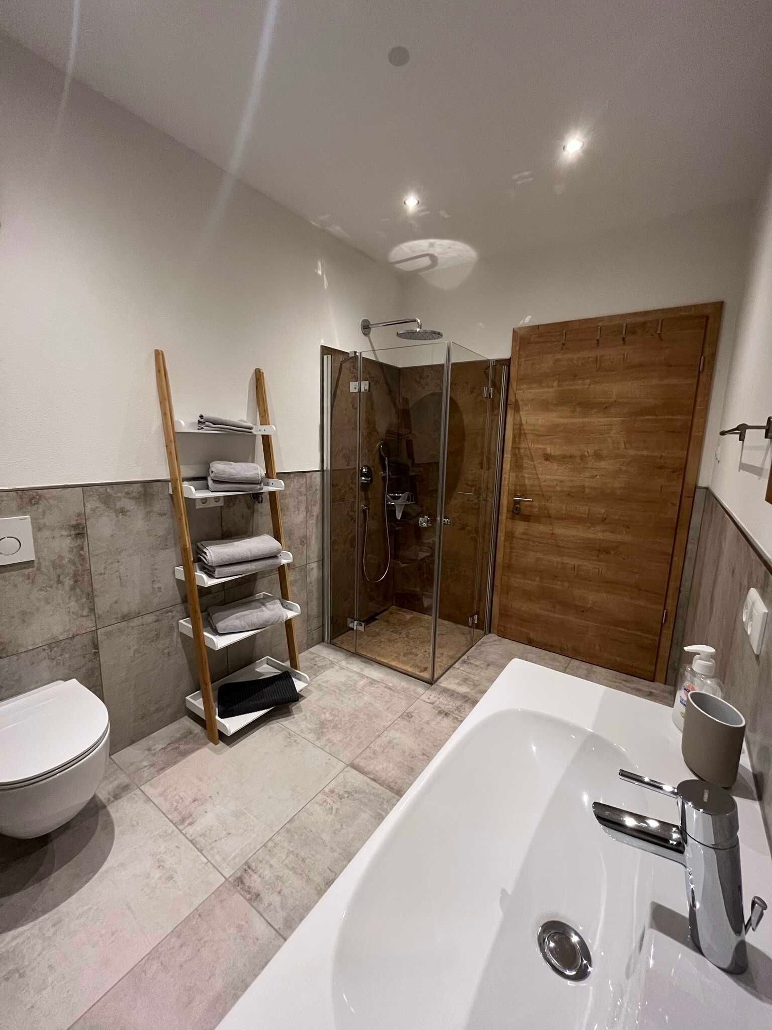 Ein modernes Badezimmer mit einer gläsernen Duschkabine, einer weißen Badewanne und einem Holzbadezimmer-Möbel.