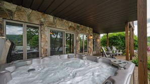 Een hottub onder een patio met een stenen bekleding en uitzicht op de omgeving.