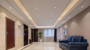 A hotel lobby with a marble floor, a blue sofa, a potted plant, and a reception desk. - Tingxi International Hotel (Changsha County)