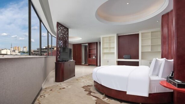 A modern hotel room with a large bed, a TV, and a view of the city. - Tingxi International Hotel (Changsha County)