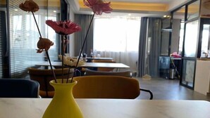 A yellow vase with dried flowers on a table in a modern interior space with large windows and a view of the outside. - Tingxi International Hotel (Changsha County)