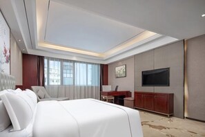 A hotel room with a large bed, a desk, a chair, a television, and a painting on the wall. - Tingxi International Hotel (Changsha County)
