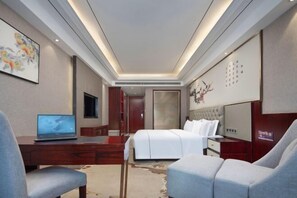 A modern hotel room with a bed, a desk with a laptop, a chair, and a television. - Tingxi International Hotel (Changsha County)