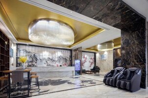 A lobby with a reception desk, massage chairs, a wall with artwork, and a marble floor.