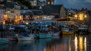 A harbor with boats docked, a clock tower, and buildings with lights. - The Decker Apartment - East Looe (East Looe)