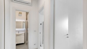 A hallway leading to a bathroom with a sink, mirror, and toilet. - Apartment "Ca Laurana 42" with Sea View, Air Conditioning and Terrace (Bibione)