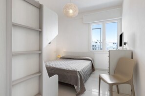 Une chambre à coucher avec un lit, une chaise, un bureau, une lampe et une fenêtre donnant sur un beau paysage.