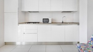 A modern kitchen with white cabinets, a microwave, a gas stove, and a stainless steel sink. - Apartment "Ca Laurana 42" with Sea View, Air Conditioning and Terrace (Bibione)