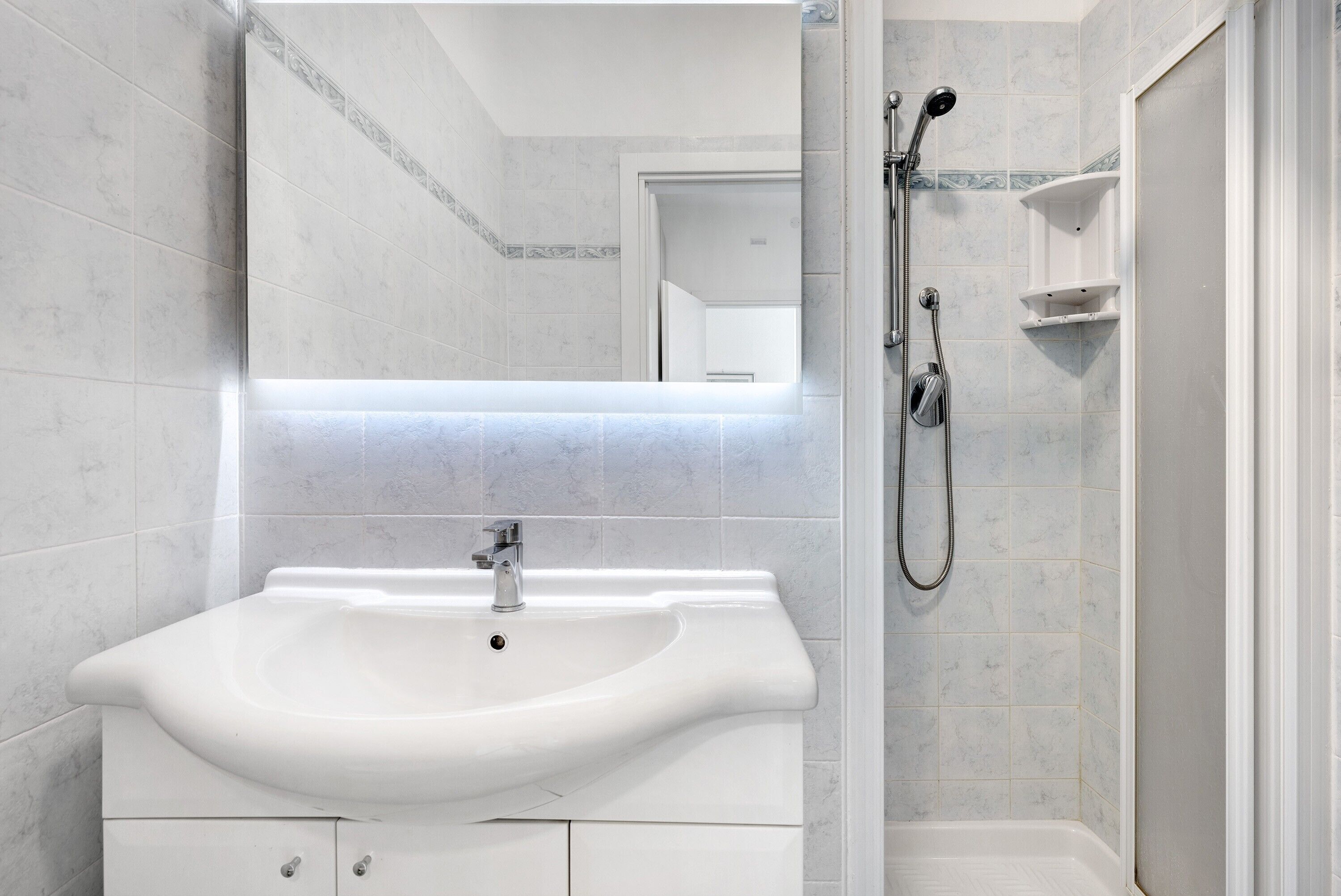 A bathroom with a white sink, a mirror, and a shower.