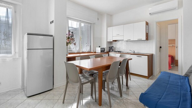 Una cucina moderna con zona pranzo, mobili bianchi e forno a microonde integrato.