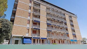Un edificio a più piani con balconi, un cartello con la scritta 'Panificio Bäckerli' e un campo sportivo verde.