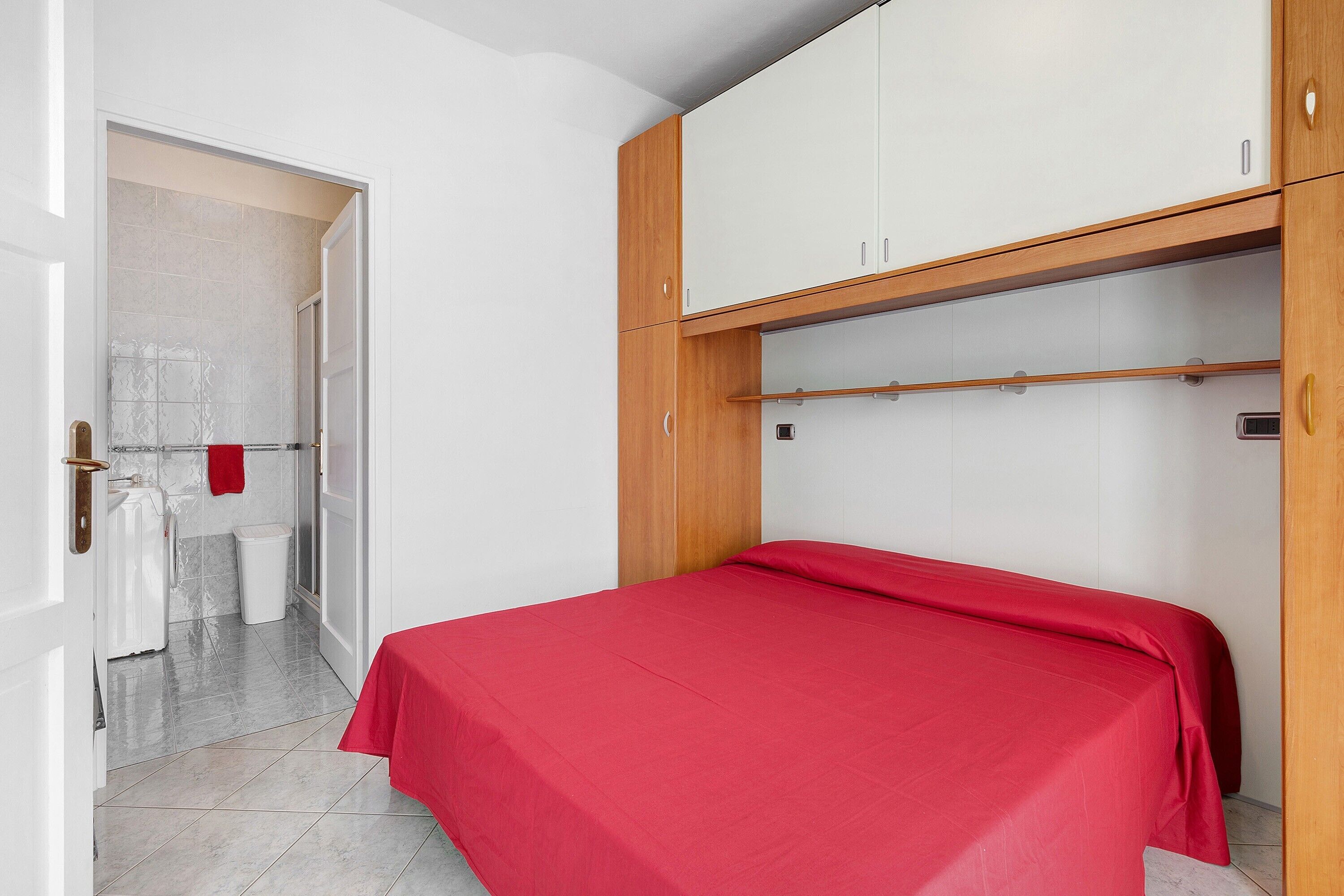 A bedroom with a bed, a wardrobe, and a bathroom visible through an open door.