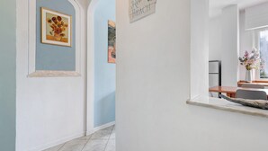 Un corridoio con un quadro incorniciato di girasoli, un cartello che riporta la scritta 'Relax Beach' e uno scorcio di una sala da pranzo con tavolo e sedie.