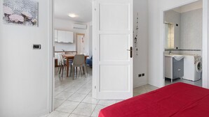 Una stanza con un letto, un'area pranzo con sedie e tavolo, e una cucina con lavatrice.