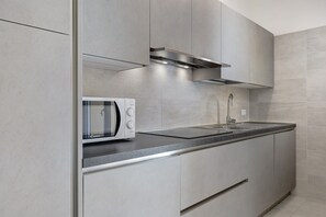 Una cocina moderna con microondas integrado, armarios de acero inoxidable y una encimera elegante.
