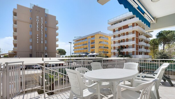 A hotel with multiple floors, outdoor seating, and a clear sky. - Apartment 'Ca Laurana 52' near the beach with garden and terrace (Bibione)