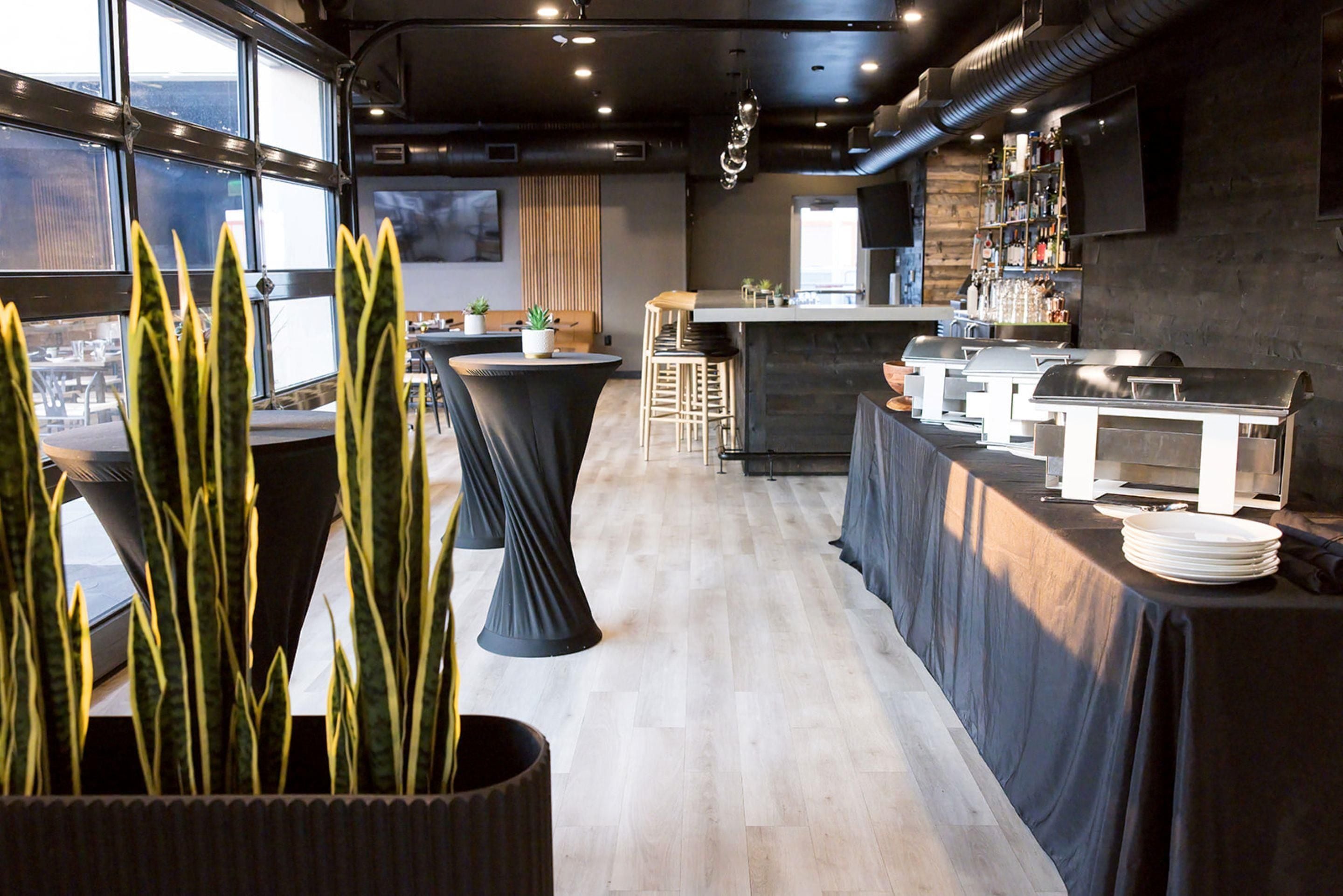 Un espace bar moderne, doté d’un comptoir, de tabourets et offrant une vue dégagée grâce à de grandes fenêtres.