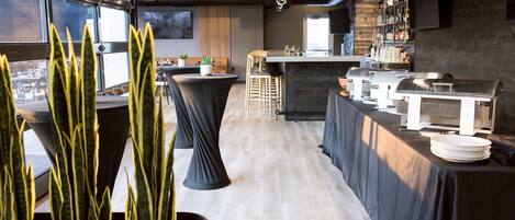 Un espace bar moderne, doté d’un comptoir, de tabourets et offrant une vue dégagée grâce à de grandes fenêtres.