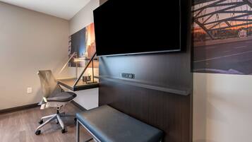 A modern office space with a mounted TV, a desk, a chair, and a bench.
