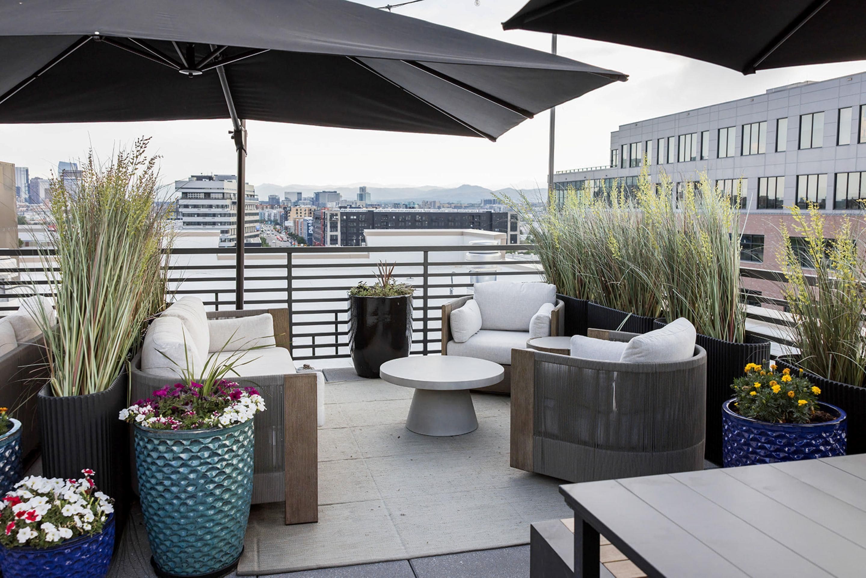 Une terrasse sur le toit, aménagée avec des espaces de détente en plein air, des plantes en pot et une vue sur le paysage urbain.