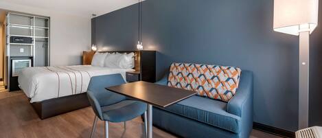 Ein modernes Hotelzimmer mit einem Bett, einer Couch, einem Tisch und einer Lampe.