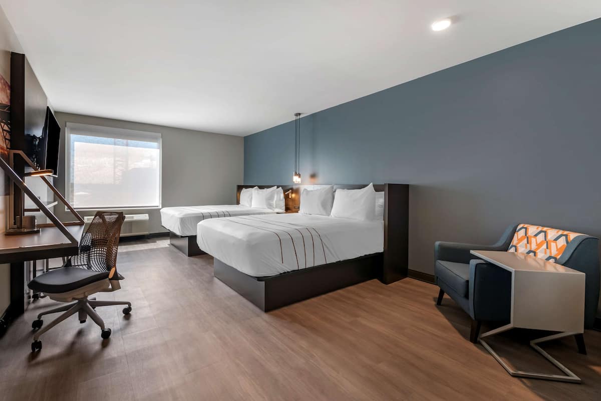 A modern hotel room with a large bed, a desk, and a chair.