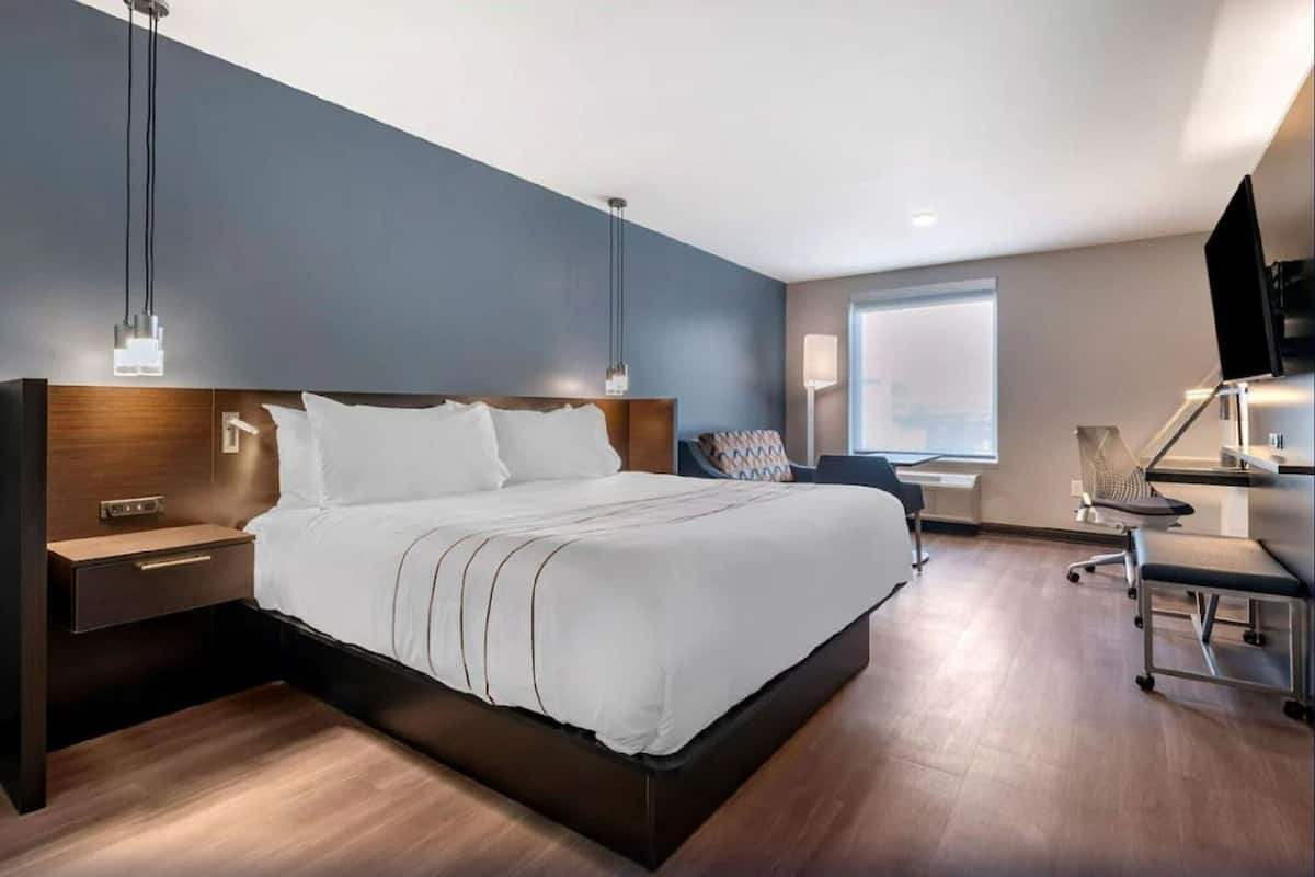 Ein modernes Hotelzimmer mit einem großen Bett, Nachttischen, einem Schreibtisch und einem Sessel.