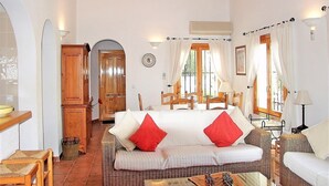A cozy room with a sofa, a dining table, and a wooden cabinet. - Costa Blanca - Villa with sea views, A/C, WiFi and pool heating in an exclusive location (Monte Pego, Alicante)
