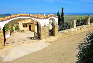 A property with a stone entrance, a paved driveway, and a view of the countryside.