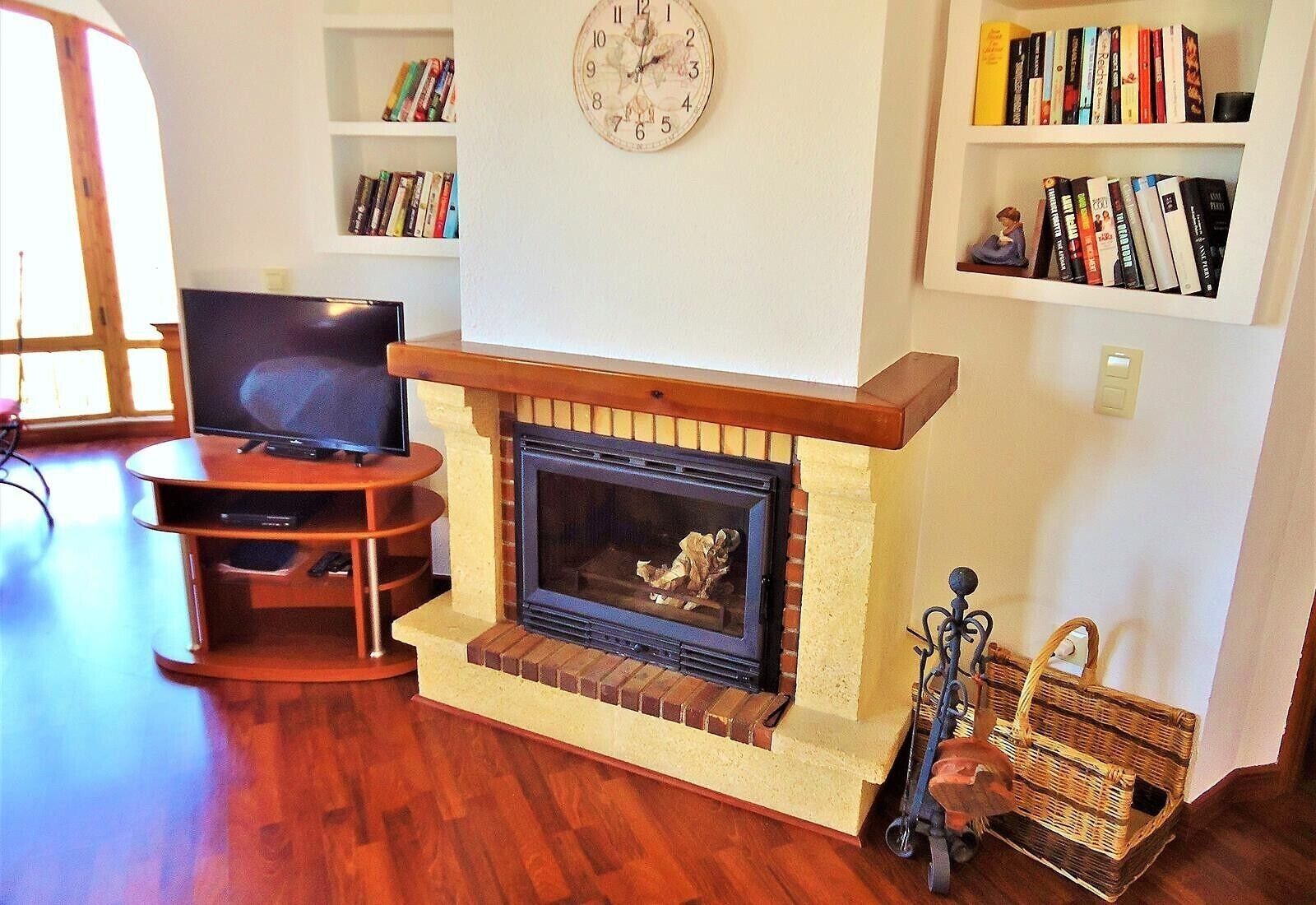 Una sala de estar con chimenea, televisor sobre un mueble bajo y estanterías.