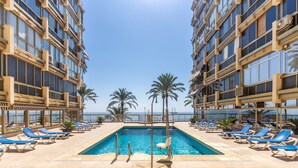 A pool area with sun loungers and a view of the sea. - Apartment 'Great First Line Amazing Terrace' with Sea View, Wi-Fi and Air Conditioning (Marbella)