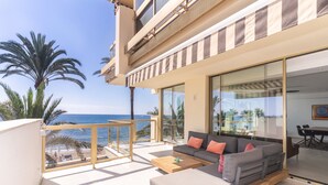 A modern outdoor living area with a sofa, coffee table, and a view of the ocean. - Apartment 'Great First Line Amazing Terrace' with Sea View, Wi-Fi and Air Conditioning (Marbella)