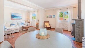 Una sala de estar con una mesa redonda, un sofá, una chimenea y vistas al exterior.