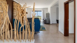 Una sala de estar moderna con una pared de piedra, un sofá azul y una escultura de madera.