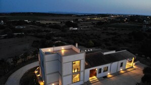 Una casa moderna de dos pisos con techo plano, ventanas grandes y entrada pavimentada.