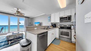 A modern kitchen with white cabinets, stainless steel appliances, and a view of the ocean.