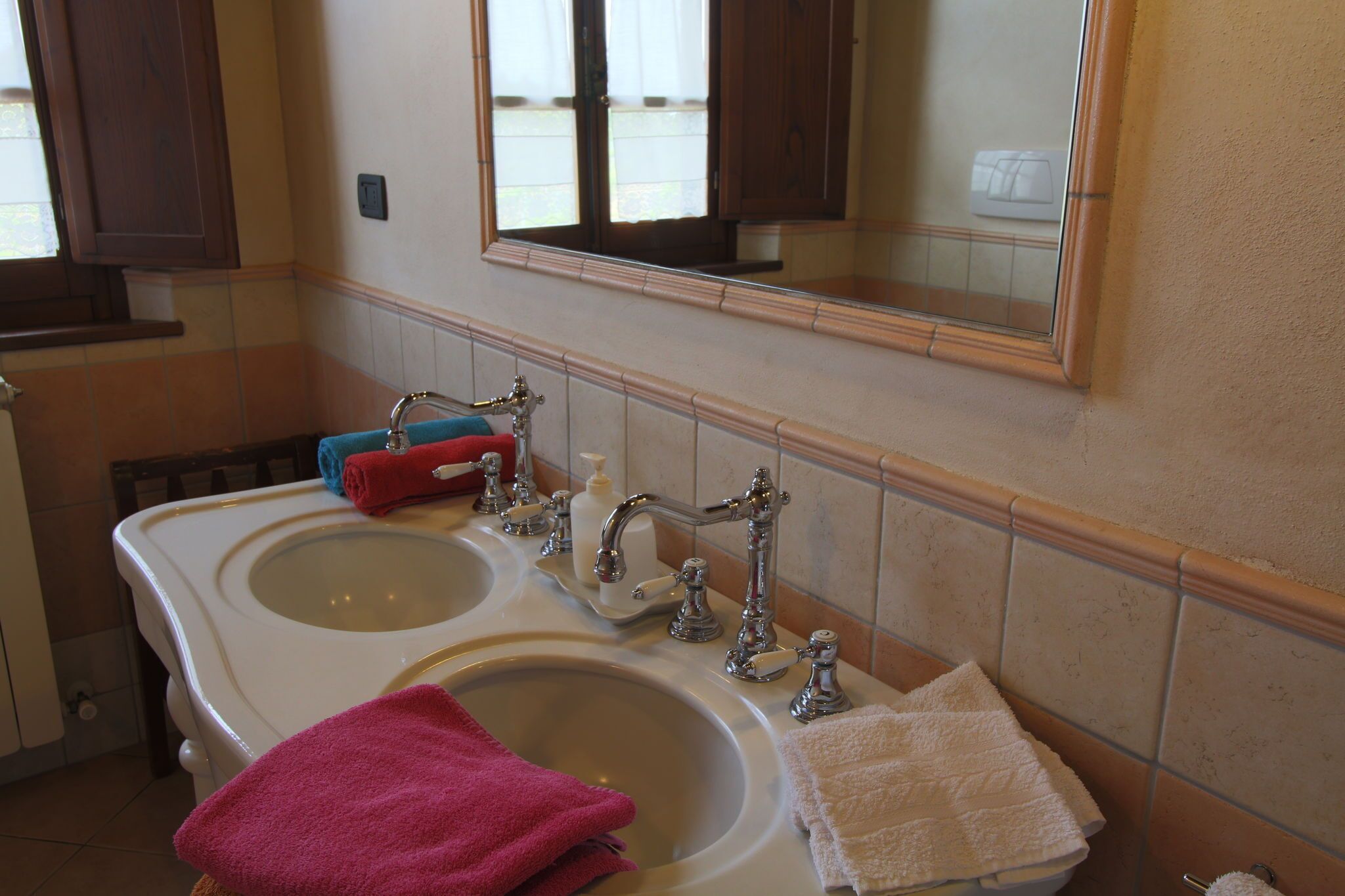 Une salle de bain avec deux lavabos, un miroir et une fenêtre.