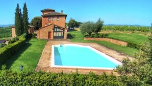 Una villa con piscina, rodeada de un césped cuidado y un viñedo.
