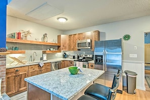 A modern kitchen with granite countertops, wooden cabinets, stainless steel appliances, and a central island. - Near Newfound Lake: Plymouth Condo w/ Fireplace! (Plymouth)